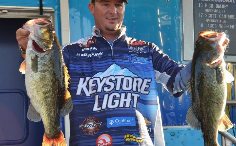 A man holding two fish while wearing a keystone light shirt.