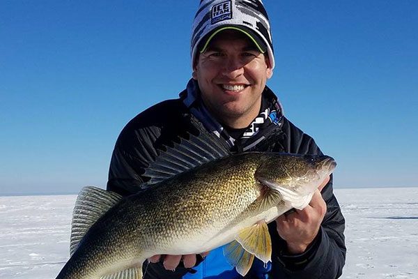 A man holding a fish while wearing a hat.